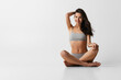 © master1305 - Young adorable woman in lingerie sitting on floor isolated over gray studio background. Natural beauty concept.