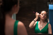 © Migue Suarez - Chica adolescente joven atractiva maquillándose el rostro junto al espejo del cuarto de baño para festejar una celebración con amigas