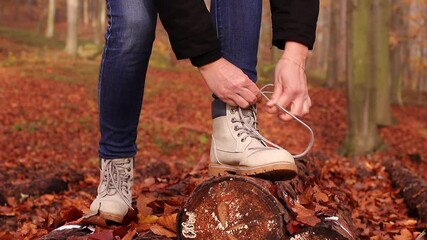 Wall Mural - woman tying shoelace on her hiking boot. tourist is getting ready for autumn hike at forest trekking