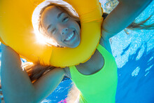 Spain, Mallorca, Smiling Woman Swimming In Pool With Inflatable Ring