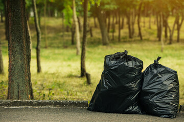 trash bags full of garbage on pavement in park. space for text