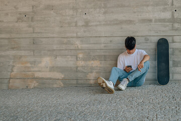 Poster - teenage boy with mobile phone and skateboard on the wall