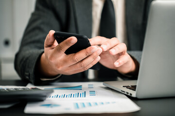 Wall Mural - Close up of businessmen using smartphone and laptop computer working business report analytic at home, accounting document, marketing and financial business concept.