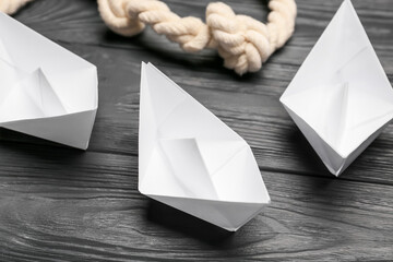 Sticker - Paper boats and rope on dark wooden background, closeup