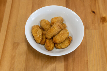 Wall Mural - Top view of the delicious crispy chicken nuggets on a white ceramic bowl on a wooden table