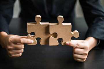 close up of businesswomen connecting couple puzzle wood jigsaw, teamwork, success, goals, strategy, partnership, business solution concept.