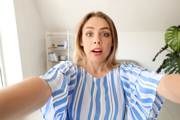 Poster - Surprised young woman taking selfie at home