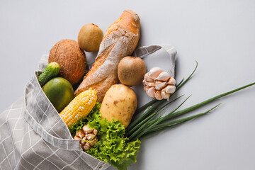 Eco bag with fruits, vegetables, greens and bread on light background, closeup