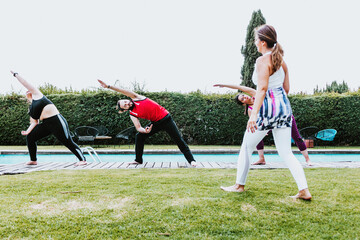 Wall Mural - Group of young latin people practicing stretching exercises with trainer in the garden in Mexico