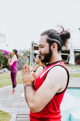 Wall Mural - Portrait of latin guy meditating calmly with closed eyes in outdoor yoga class in Latin America