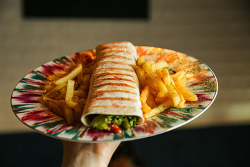 Wall Mural - chicken roll in a pita with fresh vegetables, cream sauce and french fries on wooden background.