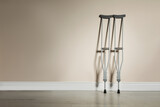 Fototapeta Paryż - Pair of axillary crutches near color wall. Space for text