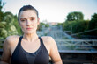 © luisrojasstock - portrait caucasian young brunette athlete woman posing and smiling looking at camera with train tracks in the background