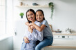 Tenderness and motherhood concept. Cute asian girl hugging mother from the back, sitting on dinner table at kitchen