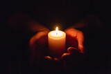 Hands holding burning candle in dark like a heart.Selective focus,black background.