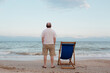 Man admires sky and sea near sun lounger on seashore