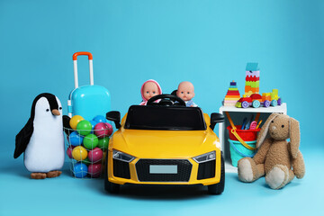 Child's electric car with other toys on light blue background