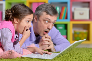 Wall Mural - Portrait of father with little daughter using laptop