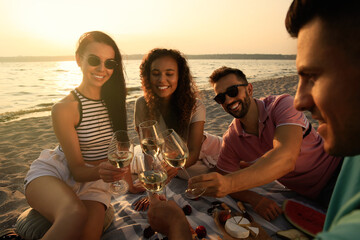 Canvas Print - Group of friends having picnic near river at sunset