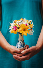 Close Up Of Woman In Blue Dress Holding A Vase Of Wildflowers.