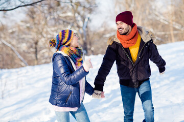 Wall Mural - Photo of cheerful young couple happy positive smile go walk run park hold hands together winter snow vacation