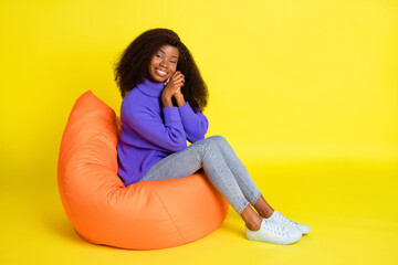 Poster - Full size profile photo of cheerful dark skin lady sit soft chair folded arms palms isolated on yellow color background