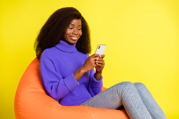 Poster - Photo of lady sit beanbag hold phone texting wear purple pullover jeans isolated yellow color background