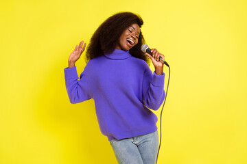 Wall Mural - Photo of pretty dark skin lady hand hold mic singing have good mood isolated on yellow color background