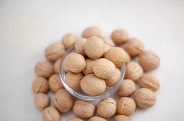 Aufkleber - A lot of whole walnuts in a cup on a white background close-up. Healthy, organic food with a high content of protein and protein.