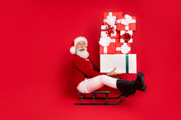 Poster - Profile side view of elderly retired cheerful Santa sleighing delivering gifts isolated over bright red color background