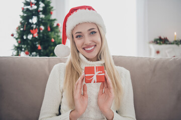 Poster - Photo of pretty adorable young lady wear knitted pullover smiling holding small present box indoors house home room