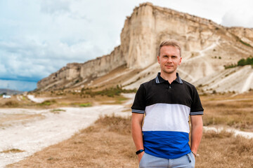 Wall Mural - Young man standing and looking out over a huge white rock, concept of travel and freedom, Crimea