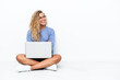 © luismolinero - Girl with curly hair with a laptop sitting on the floor looking side