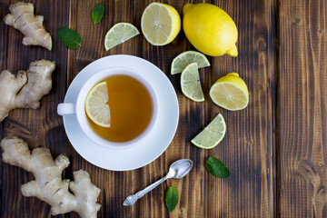 Wall Mural - Top view of tea in the white cup with lemon and ginger on the wooden background. Copy space.