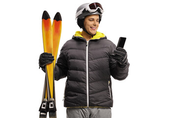 Wall Mural - Young man with a skiing equipment smiling and looking at a mobile phone