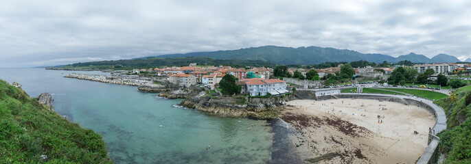 panoramic view of Llanes, Asturias, Spain, with the beach in the foreground, the entrance to the harbor and the downtown area in the background