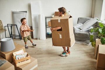 Wall Mural - Full length portrait of two brothers wearing cardboard boxes and playing while family moving to new house, copy space