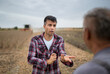 © Budimir Jevtic - Two male farmers standing in harvested soy field talking.