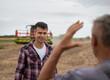 © Budimir Jevtic - Two male farmers standing in harvested soy field talking.