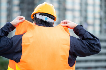 Wall Mural - Asian maintenance worker man wearing reflective vest and safety helmet working at construction site. Civil engineering, Architecture builder and building service concepts
