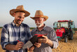 © Budimir Jevtic - Young farmer and senior agronomist signing documents in field with machinery in background.