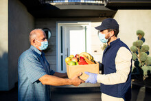 Senior Man Accepting Food Delivery From Deliveryman During Covid19 Pandemic Or Lockdown.