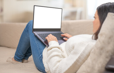Poster - Mockup laptop. Woman looking at mock up blank white screen lying on sofa at home. woman using, working on laptop with blank screen while sitting on sofa in living room. mockup template.