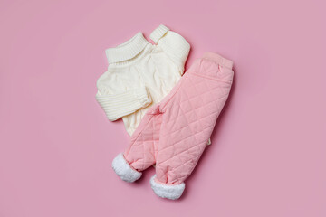 Wall Mural - White sweater and warm pants on pink background. Stylish childrens outerwear. Winter fashion outfit
