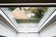 Abstract view of a newly installed skylight window in a loft conversion. Distant bungalows can be seen on a raining day.