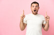 © luismolinero - Young Brazilian man isolated on pink background surprised and pointing up