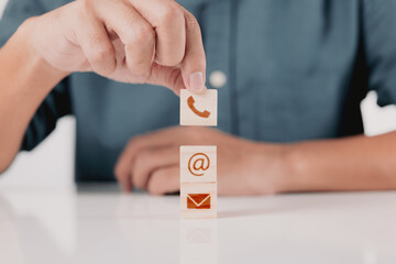 Poster - Businessman with phone, email, and address on a wooden block cube symbol. Contact us page on the website or email marketing concept