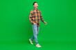 Full length body size view of attractive cheerful man going wearing cozy clothes isolated over bright green color background