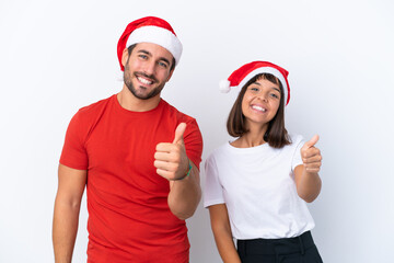 Wall Mural - Young couple with christmas hat isolated on white background giving a thumbs up gesture because something good has happened