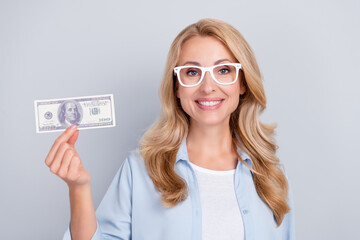 Sticker - Photo of cheerful candid lady hold dollar promote bank service wear specs blue shirt isolated grey color background